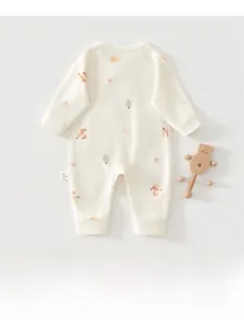 Detail of baby cotton romper with soft holiday prints and a wooden bear toy nearby