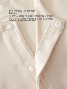 Detail of food-grade resin snap buttons on breathable baby bodysuit with fine stitching