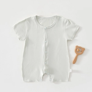 Close-up of soft breathable baby romper with snap buttons and wooden bear rattle accessory