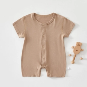 Detail of soft modal cotton baby romper with buttons and a small wooden bear toy