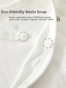 Macro shot of food-grade POM resin snap button on soft white cotton baby kimono top