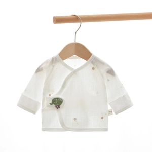Close-up of white 100% cotton gauze baby kimono top with green elephant pattern