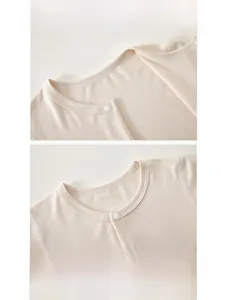 Detailed view of the smooth bound neckline and resin snaps on the baby cotton bodysuit