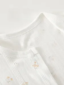 Détail de la barboteuse respirante pour bébé avec motif floral et bouton pression