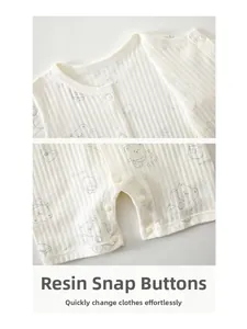 Détail d'un barboteuse rayée pour bébé avec pressions en résine et motif d'ours