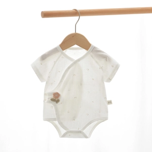 Dettaglio della tutina per neonati in cotone floreale con bottoni e fiore 3D applicato