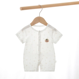 Détail d'une barboteuse d'été blanche pour bébé avec motif floral et broderie cerise