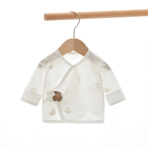 Detail of white cotton newborn baby tie-up kimono top with a small bear embroidery