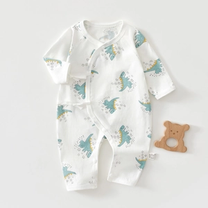 Détail d'une barboteuse bébé en coton doux avec imprimés dinosaures bleus et nouettes