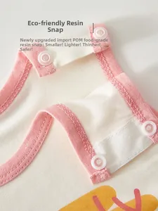 Detail of eco-friendly POM resin snaps on white cotton baby bodysuit with pink trim