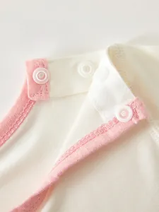 Close-up of baby romper collar featuring high-quality white resin snap buttons on pink cotton