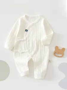 Detailed view of cream-colored baby romper with rib knit texture and side-tie ribbon