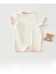 Close-up of baby short sleeve cotton romper with pink trim and wooden bear toy