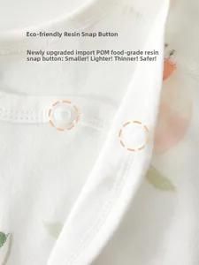 Close-up of eco-friendly resin snap buttons on newborn cotton bodysuit with orange print