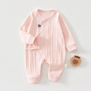 Detail of soft pink cotton baby romper with fine ribbed texture and bow tie closure
