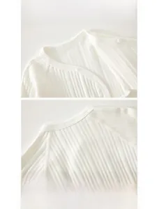 Detail view of soft white cotton rib knit baby bodysuit with fine stitching and resin button
