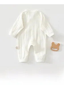 Detailed macro view of white ribbed cotton baby bodysuit and a wooden bear teether toy