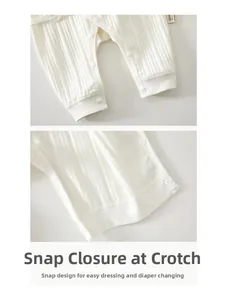 Detailed view of snap closure on white ribbed cotton newborn bodysuit for easy changing