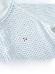 Detail of light blue baby bodysuit featuring rib-knit fabric and cute cartoon bear print