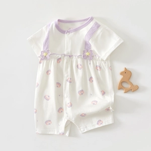 Gros plan d'un body blanc pour bébé avec liseré violet, pois colorés et fleurs en 3D