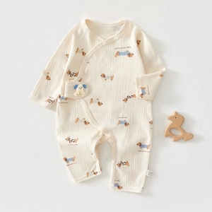Close-up of cream newborn romper with puppy print and side snap closure design