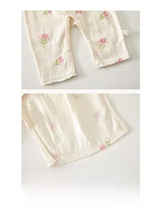 Detailed macro view of white muslin baby romper with pink tulip print and snap buttons