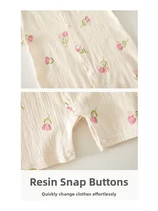 Détail d'un barboteuse pour bébé avec boutons pression en résine et motif tulipe en coton