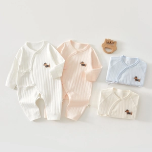 Detail of soft cotton baby bodysuits showing rib-knit texture and dog embroidery