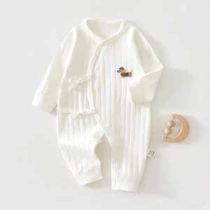 Detail of white cotton baby romper featuring a cute dog embroidery and side-tie closure