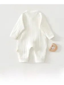 Detail of soft ribbed cotton baby romper fabric with minimalist wooden moon rattle decoration