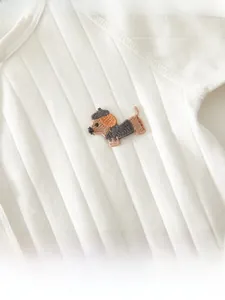Detail of white cotton rib-knit baby romper with cute dachshund dog embroidery motif