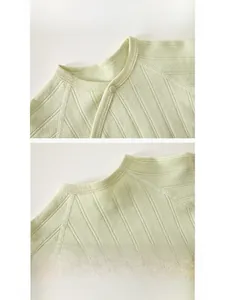 Detailed view of reinforced neckline with snap button on soft green newborn knit top