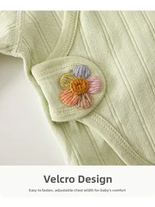 Detail of newborn cotton shirt featuring adjustable velcro closure and a colorful flower motif