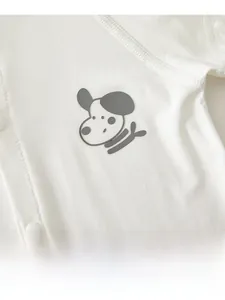 Detailaufnahme des Baby-Stramplers mit Cartoon-Hund-Patch und Druckknöpfen auf weicher Baumwolle