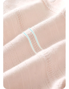 Close-up of pink breathable cotton knit fabric with pointelle texture and overlock seams