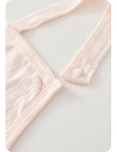 Detail of baby pink cotton bib with white resin snaps and breathable jacquard knit texture