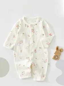 Detail of baby cotton jumpsuit featuring cute pink cherry and bunny print with snap buttons