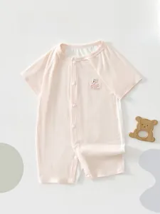 Close-up of baby pink romper with swan embroidery and wooden bear teething toy