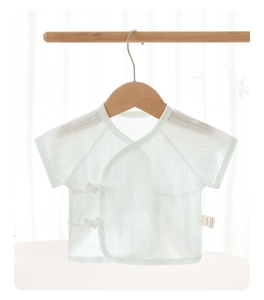 Close-up of mint green newborn cotton top with mesh texture and lace-up closure