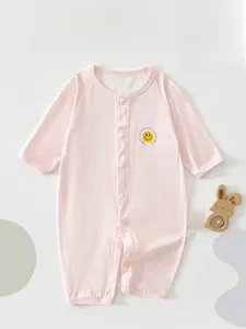 Close-up of pink long-sleeve baby romper with smiley face print and white buttons