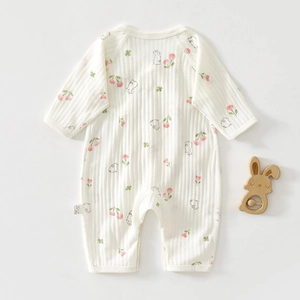 Détail d'une barboteuse bébé côtelée avec imprimés tulipes et lapins et hochet en bois