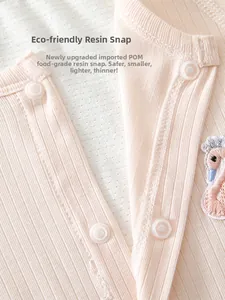 Detail of baby romper featuring pink ribbed cotton fabric and swan embroidery patch