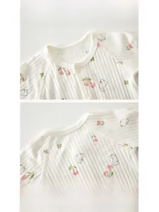 Detail of baby cotton onesie featuring piped neckline and pink floral rabbit prints