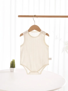 Sleeveless ribbed cotton newborn bodysuit in off-white hanging on a wooden hanger