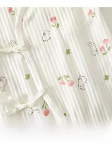Détail d'une barboteuse bébé en coton côtelé avec motif lapin fleuri et nœuds latéraux