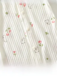 Macro view of baby romper featuring pink flower and bunny prints on white ribbed fabric