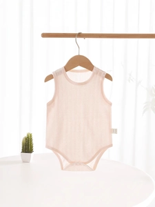 Pink ribbed sleeveless baby bodysuit in pure cotton on a wooden hanger with soft lighting