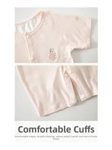 Detail of pink baby bodysuit showing ribbed fabric texture and fine swan embroidery