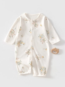 Detail of baby cotton romper with cartoon rabbit prints and wooden cat teether prop