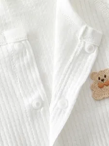 Close-up of white waffle texture fabric with eco-friendly resin snaps and bear embroidery
